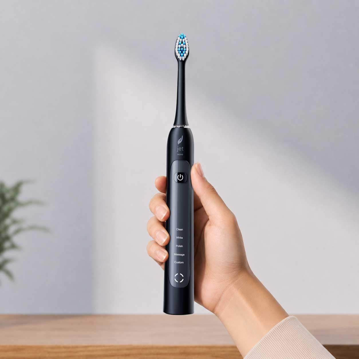 Hand holding a black electric toothbrush with a blurred background